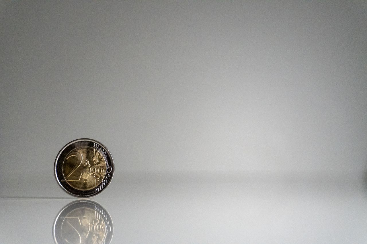 Services A minimalist image of a 2 euro coin with reflection on a sleek surface.