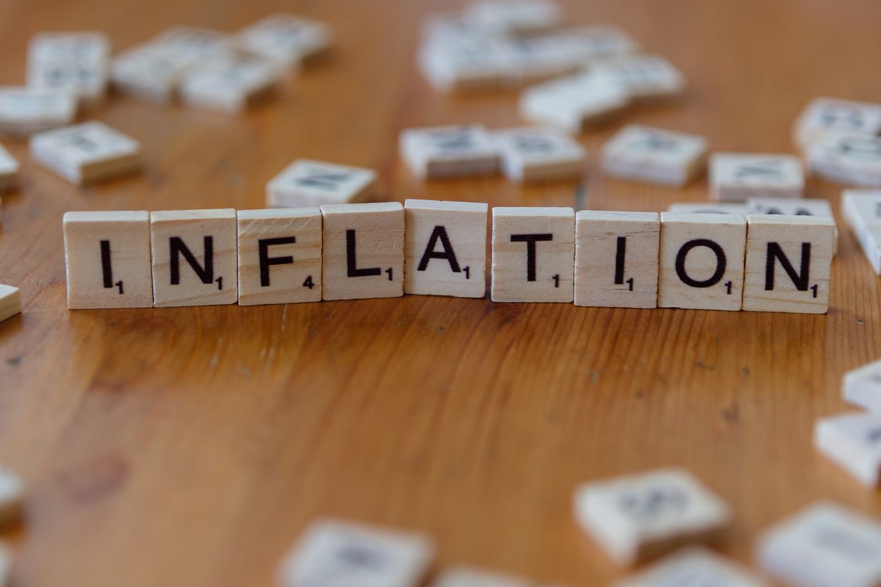 Services Scrabble letter tiles spelling 'INFLATION' on a wooden table, signifying economic concepts.