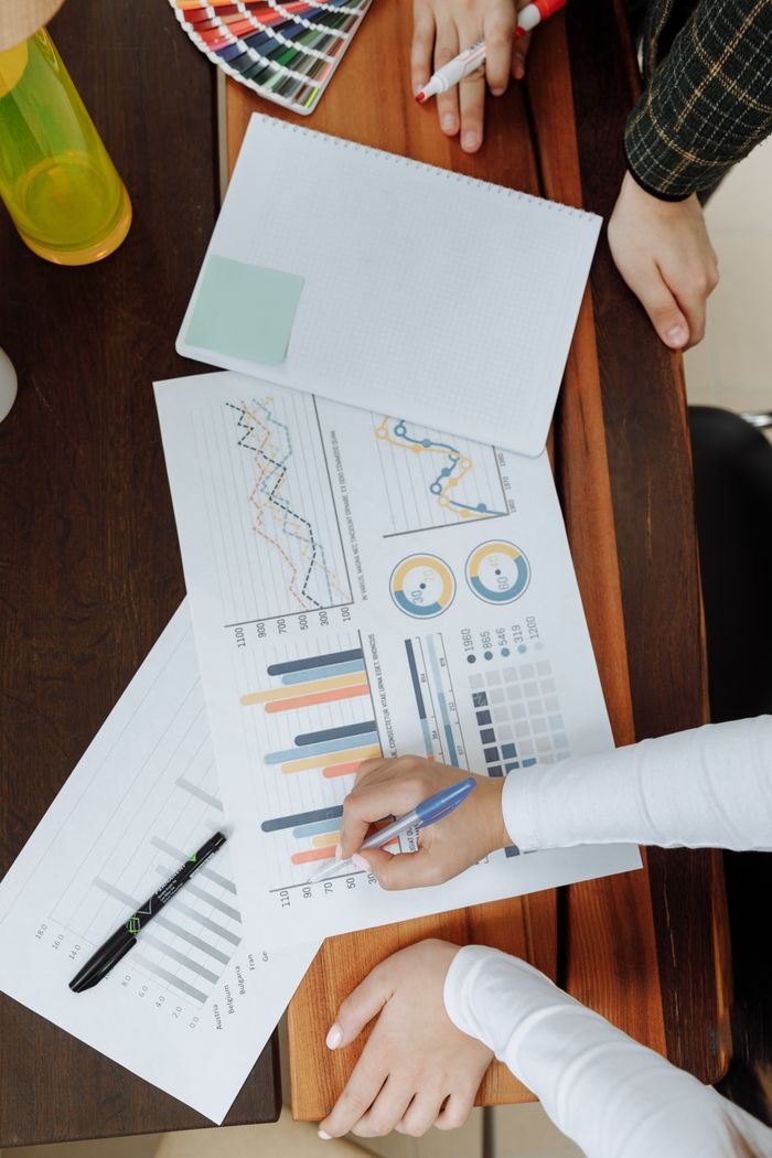 About Top view of business team analyzing charts and data on paper for strategic planning.